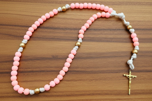 Paracord rosary with pink and gold beads on a wood background