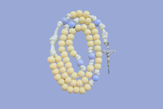 Rosary with yellow and blue pastel colored beads with a silver crucifix on a gray background