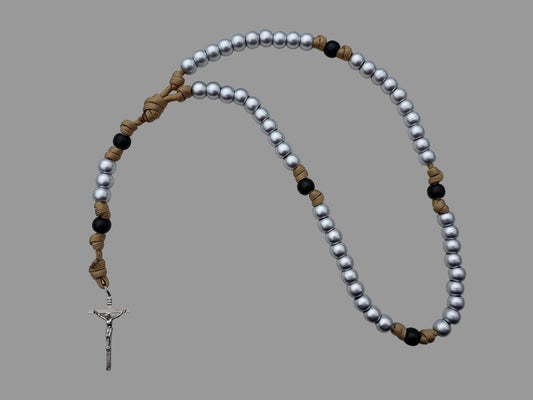 Durable paracord rosary with shiny silver beads and matte black beige/gold accents on a light gray background